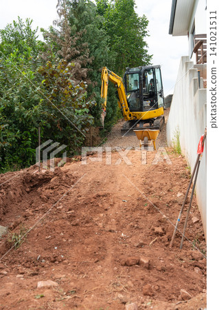 A bustling construction site with an excavator actively digging, offering a ground-level view of dirt piles and surrounding trees, all set against a backdrop of brown and green hues. A bustling construction site with an excavator actively digging, offering a ground-level view of dirt piles and surrounding trees, all set against a backdrop of brown and green hues. 141021511
