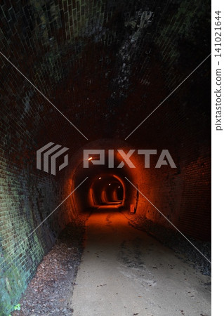A retro tunnel illuminated by orange lights; a mysterious landscape of an abandoned railway line. 141021644