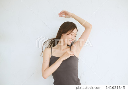 A young woman in a camisole poses, showing her armpits. A young woman in a camisole poses, showing her armpits. 141021845