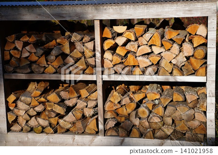 Winter preparations and a mindful lifestyle: The sight of neatly split firewood arranged on a firewood rack. Winter preparations and a mindful lifestyle: The sight of neatly split firewood arranged on a firewood rack. 141021958