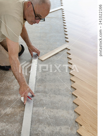 Carpenter measuring and marking layout for Italian herringbone parquet flooring installation Carpenter measuring and marking layout for Italian herringbone parquet flooring installation 141022166