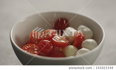 making salad with mozzarella and cherry tomatoes, caprese style in white bowl closeup making salad with mozzarella and cherry tomatoes, caprese style in white bowl closeup 141023144