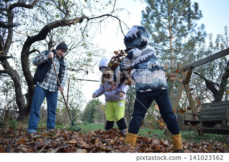 Young father, pre-teen daughter and son in warm autumn clothes spending quality time together among fallen leaves. Happy family enjoying the beauty of fall, playful moments and family life outdoors Young father, pre-teen daughter and son in warm autumn clothes spending quality time together among fallen leaves. Happy family enjoying the beauty of fall, playful moments and family life outdoors 141023562