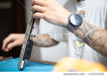 Technician works on computer hardware in a workshop during the day Technician works on computer hardware in a workshop during the day 141023605