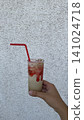 Refreshing Summer Drink Photo with Strawberry Cream Beverage, Red Straw and Ice in Hand, Minimal Cocktail Mocktail Image with White Textured Wall and Copy Space 141024718