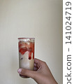 Strawberry Cream Iced Drink Photo in Hand with Sugar Rim, Refreshing Summer Mocktail with Copy Space on Minimal Light Background for Cafe Menu and Beverage Design 141024719