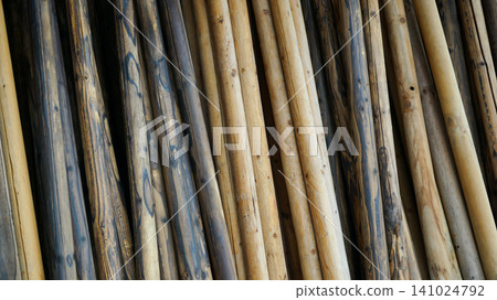 Stacked natural round wooden logs and timber poles Stacked natural round wooden logs and timber poles 141024792