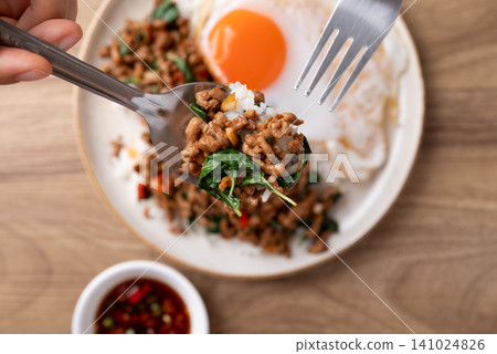 Eating Thai food, Stir-fried holy basil with minced pork with cooked rice and fried egg Eating Thai food, Stir-fried holy basil with minced pork with cooked rice and fried egg 141024826