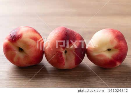 Close-up of fresh white peaches with water droplets on a wooden background, Summer fruit Close-up of fresh white peaches with water droplets on a wooden background, Summer fruit 141024842