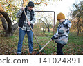 Young father, pre-teen daughter and son in warm autumn clothes spending quality time together among fallen leaves. Happy family enjoying the beauty of fall, playful moments and family life outdoors 141024891