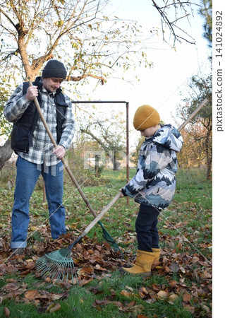 Young father, pre-teen daughter and son in warm autumn clothes spending quality time together among fallen leaves. Happy family enjoying the beauty of fall, playful moments and family life outdoors 141024892