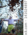 Young father, pre-teen daughter and son in warm autumn clothes spending quality time together among fallen leaves. Happy family enjoying the beauty of fall, playful moments and family life outdoors 141024897