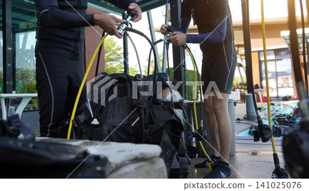 Professional scuba diver instructs the novice how to use the equipment before dive Professional scuba diver instructs the novice how to use the equipment before dive 141025076
