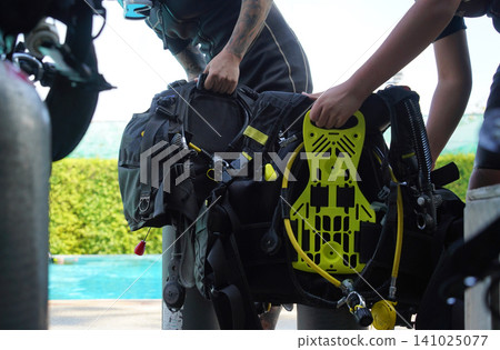 Professional scuba diver instructs the novice how to use the equipment before dive Professional scuba diver instructs the novice how to use the equipment before dive 141025077