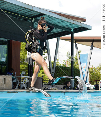A professional diver and a novice practice diving in a pool. A professional diver and a novice practice diving in a pool. 141025090