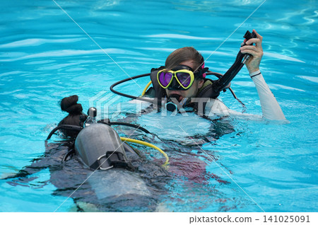 A professional diver and a novice practice diving in a pool. A professional diver and a novice practice diving in a pool. 141025091