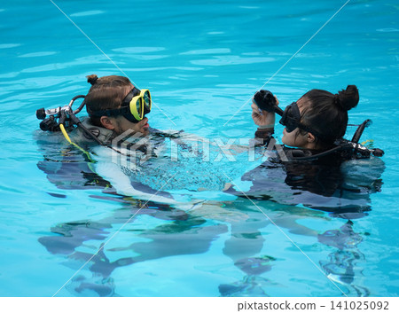 A professional diver and a novice practice diving in a pool. A professional diver and a novice practice diving in a pool. 141025092