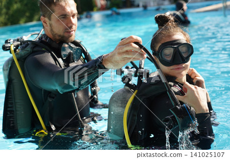 Dive instructor checking novice the diving equipment before diving Dive instructor checking novice the diving equipment before diving 141025107