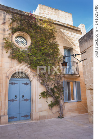Maltese facade in Mdina with blue doors, shutters, and climbing bougainvillea Maltese facade in Mdina with blue doors, shutters, and climbing bougainvillea 141025480