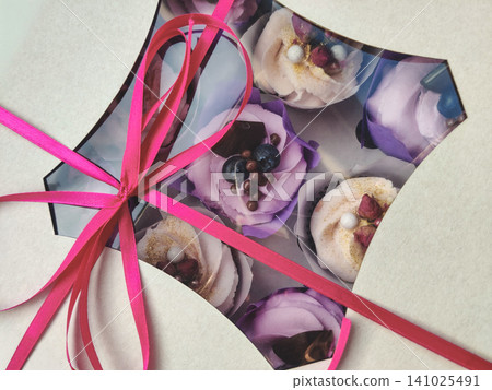 Box of decorated cupcakes with a vibrant pink ribbon Box of decorated cupcakes with a vibrant pink ribbon 141025491