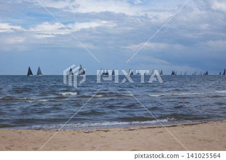 Sailing yachts regatta on a choppy sea near a sandy beach Sailing yachts regatta on a choppy sea near a sandy beach 141025564