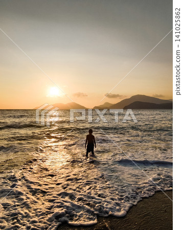 silhouette of children to swim in the sea at sunset 141025862