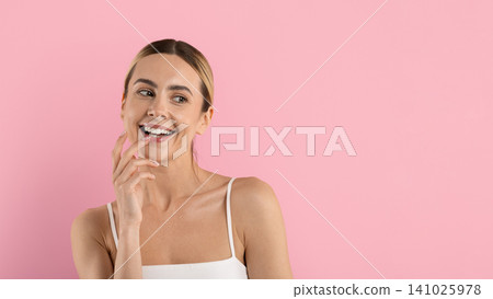 Young beautiful woman smiling and touching her lips on pink studio background Young beautiful woman smiling and touching her lips on pink studio background 141025978