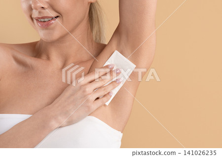 Closeup of young beautiful woman using white tissue on her underarm Closeup of young beautiful woman using white tissue on her underarm 141026235