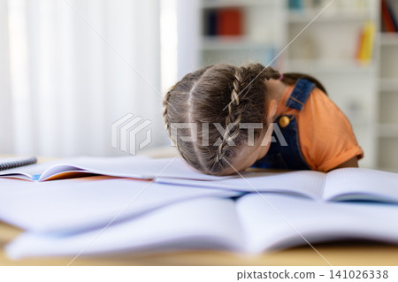 Exhausted teen girl resting her head down on open notebook at desk Exhausted teen girl resting her head down on open notebook at desk 141026338