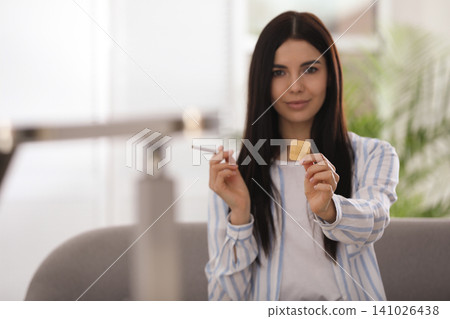 Happy young woman with nicotine patch and cigarette at home. Space for text Happy young woman with nicotine patch and cigarette at home. Space for text 141026438