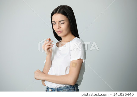 Emotional young woman with nicotine patch and cigarette on light grey background Emotional young woman with nicotine patch and cigarette on light grey background 141026440