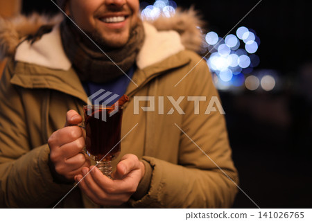 Man with tasty mulled wine at winter fair, closeup 141026765