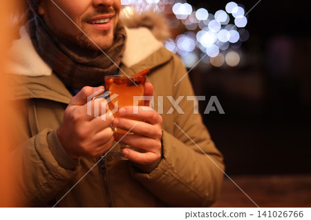 Man with tasty mulled wine at winter fair, closeup 141026766