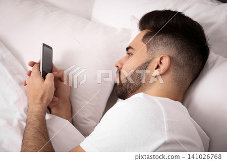 Young man addicted to smartphone in bed at home Young man addicted to smartphone in bed at home 141026768