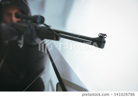 Hired professional killer indoors, focus on sniper rifle Hired professional killer indoors, focus on sniper rifle 141026786
