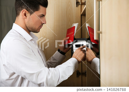 Man opening black steel safe with electronic lock at hotel Man opening black steel safe with electronic lock at hotel 141026788