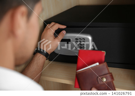 Man opening black steel safe with electronic lock at hotel, closeup Man opening black steel safe with electronic lock at hotel, closeup 141026791