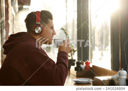Man listening to audiobook at table in cafe Man listening to audiobook at table in cafe 141026804
