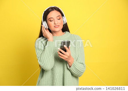 Young woman listening to audiobook on yellow background Young woman listening to audiobook on yellow background 141026811
