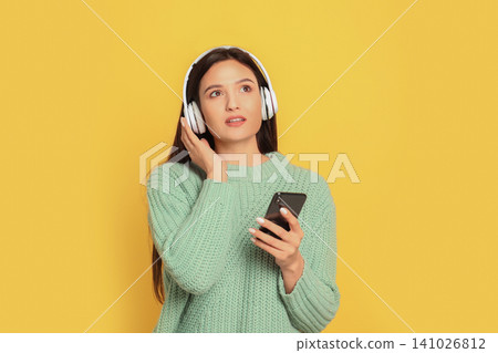 Young woman listening to audiobook on yellow background Young woman listening to audiobook on yellow background 141026812