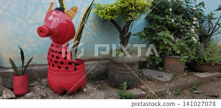 A creative, red, animal-shaped plant pot made from a recycled plastic bottle in a home garden. A creative, red, animal-shaped plant pot made from a recycled plastic bottle in a home garden. 141027078