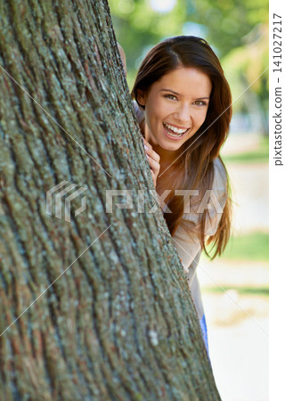 Woman, park and tree with hide, smile and portrait with happiness and green fun for nature. Lady, laugh and sun with grass, forest and happy for excited playful summer with optimism and sunshine Woman, park and tree with hide, smile and portrait with happiness and green fun for nature. Lady, laugh and sun with grass, forest and happy for excited playful summer with optimism and sunshine 141027217
