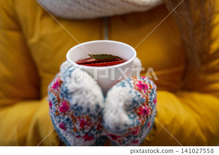 Woman in yellow jacket holding cup of mulled wine, closeup 141027558
