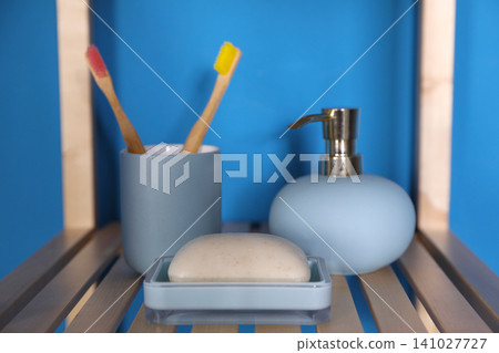 Shelving unit with toiletries near blue wall indoors. Bathroom interior element Shelving unit with toiletries near blue wall indoors. Bathroom interior element 141027727
