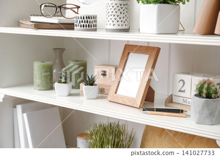 White shelving unit with plants and different decorative stuff 141027733