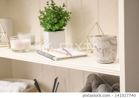White shelving unit with notebook and different decorative stuff, closeup 141027740