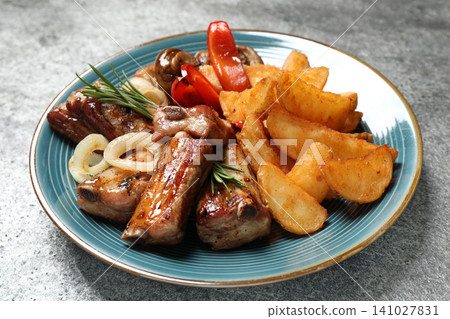 Delicious grilled ribs and garnish on grey table Delicious grilled ribs and garnish on grey table 141027831