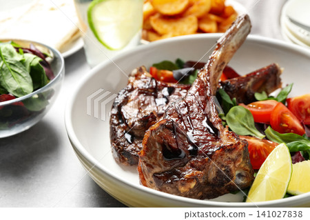 Delicious grilled ribs served on light grey table, closeup Delicious grilled ribs served on light grey table, closeup 141027838