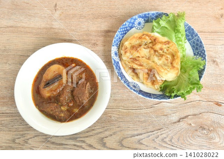 spicy beef meat massaman curry eat cuople with slice crispy roti and baby cos lecctue on white bowl 141028022