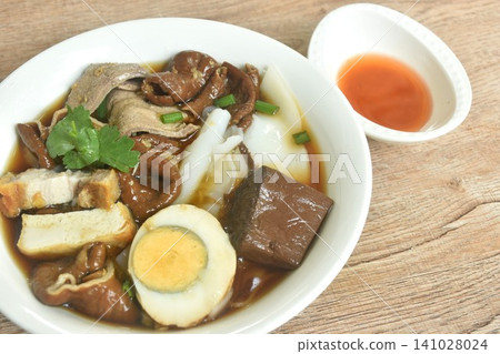 Chinese rice flour paste with pork and entrails topping boiled egg in herb brown soup on bowl dressing spicy chili vinegar sauce Chinese rice flour paste with pork and entrails topping boiled egg in herb brown soup on bowl dressing spicy chili vinegar sauce 141028024
